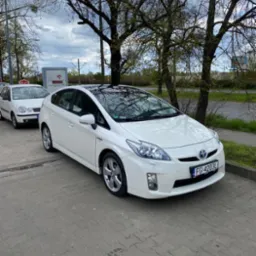 Biały samochód typu hatchback z czarnym dachem panoramicznym zaparkowany na chodniku z widoczną tablicą rejestracyjną FG 4203L.