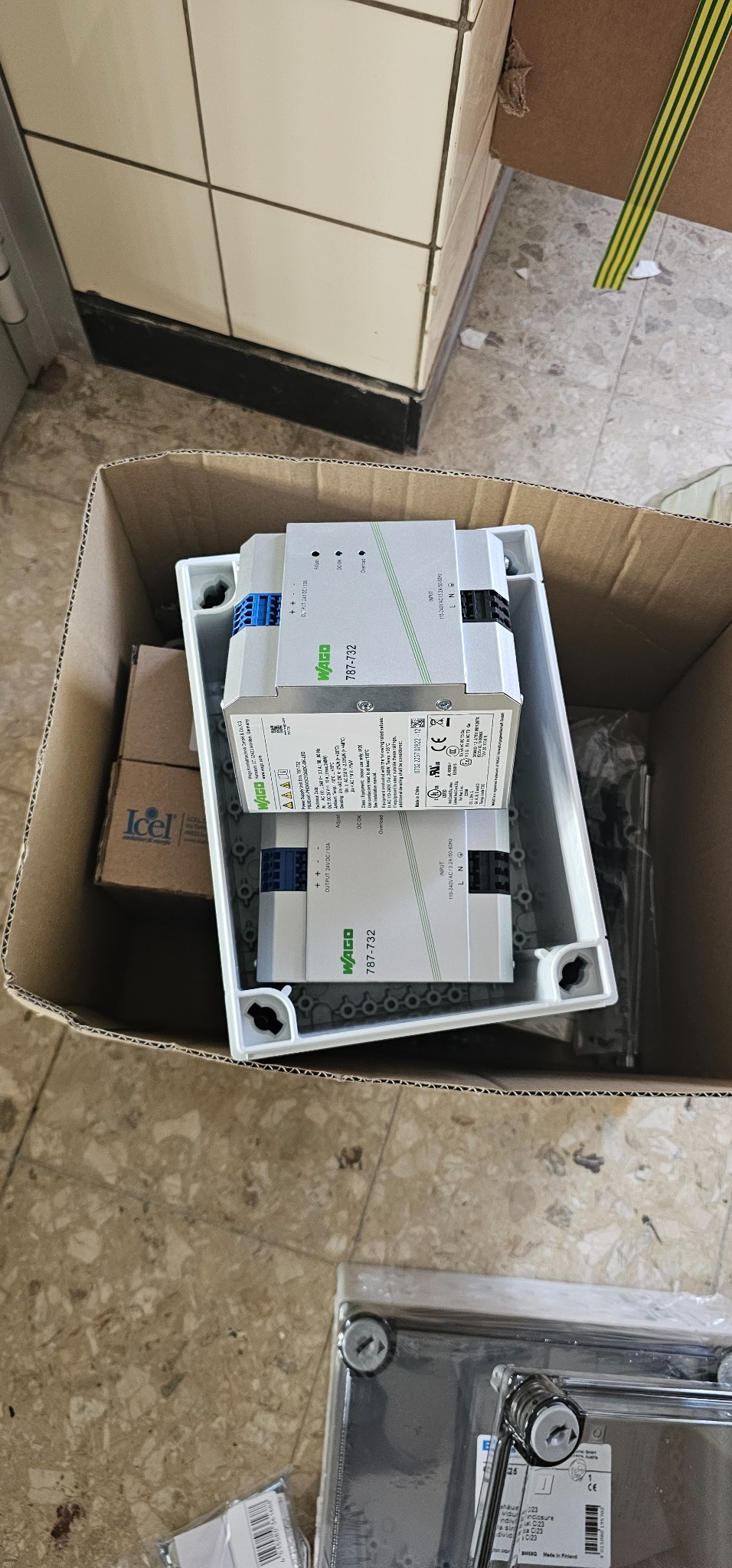 Dwa zasilacze WAGO 787-732 w białej obudowie, zapakowane w karton, widoczne niebieskie złącza i etykiety z danymi technicznymi.