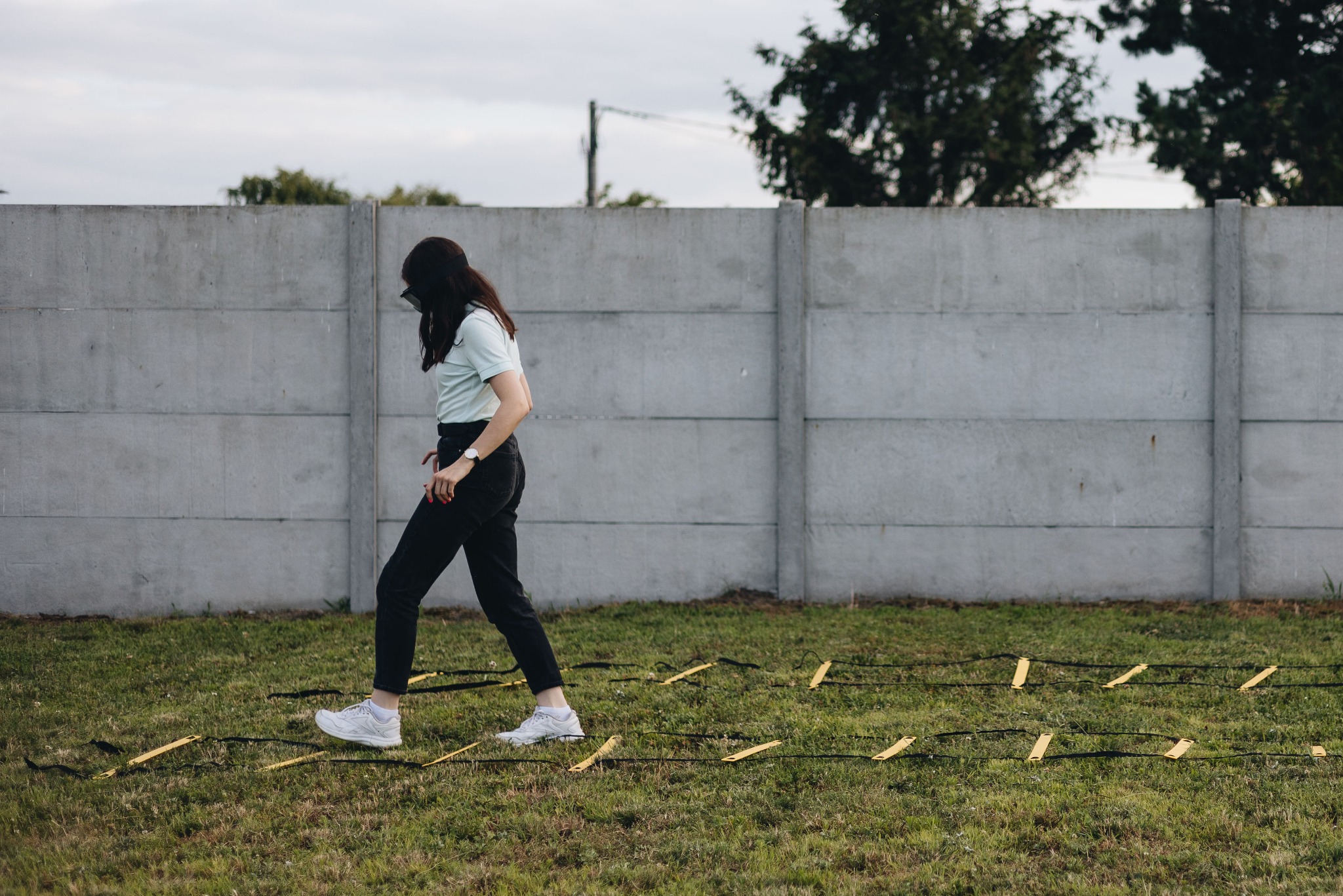 Osoba w alkogoglach przechodzi przez tor przeszkód na trawie, element ćwiczenia symulującego stan upojenia alkoholowego.