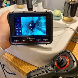 WaterLeak.pl - Osuszanie Budynków Wykrywanie Wycieków Wody Wynajem Osuszaczy Lokalizacja Przecieków Gdynia Gdańsk Sopot Warszawa - Kamera inspekcyjna Mitcorp z widokiem wnętrza rury kanalizacyjnej na ekranie, obok umywalki i dozownika mydła w łazience.