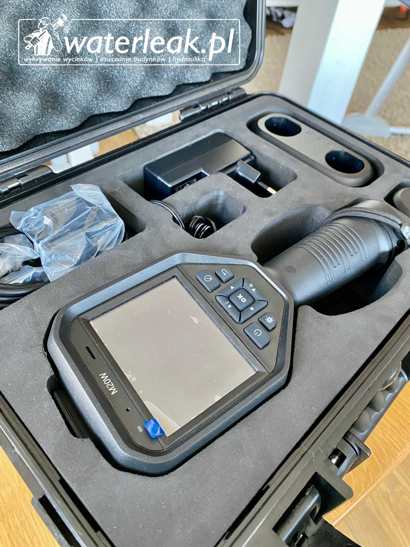 Kamera termowizyjna M20W w czarnym, wyściełanym etui, z widocznymi przyciskami sterującymi i akcesoriami, używana do wykrywania wycieków.