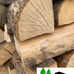 PRZEDSIĘBIORSTWO HANDLOWO - USŁUGOWE KRZYSZTOF TONDAŚ - Stos drewna kominkowego, z widocznym przekrojem pnia i korą. Na pierwszym planie logo firmy. Jasne drewno ułożone w stos, gotowe do użycia.