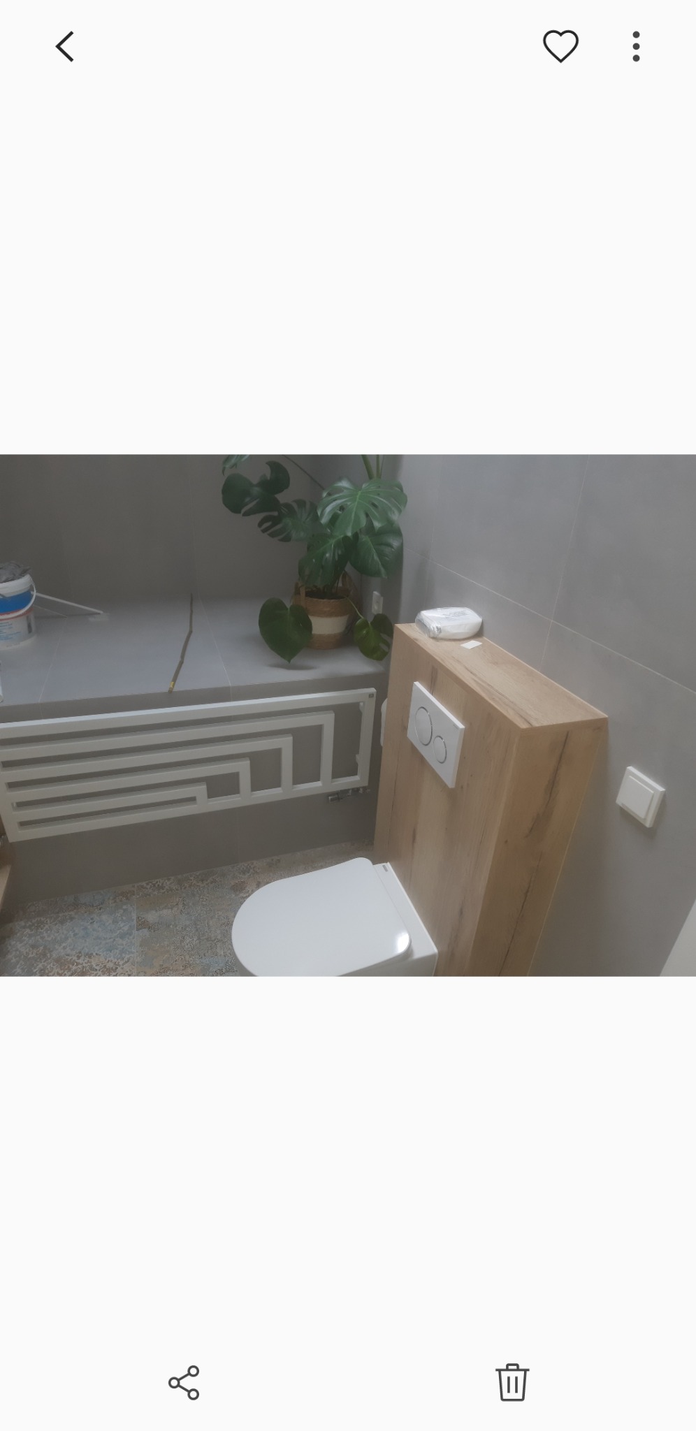 Nowoczesna łazienka z podtynkową toaletą, grzejnikiem drabinkowym i rośliną Monstera w doniczce.