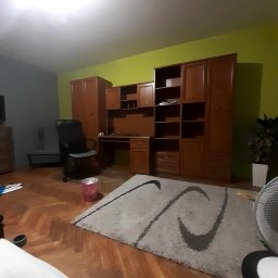 Usługi Remontowo-Wykończeniowe JAK-BUD Kacper Jakubiak - Pokój z drewnianymi meblami, dywanem z wzorem i parkietem w jodełkę, ściana w kolorze limonkowym, widok z dołu