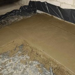 Usługi Remontowo-Wykończeniowe JAK-BUD Kacper Jakubiak - Wyrównywanie podłoża w piwnicy w trakcie prac remontowych; widoczna wylewka betonowa, folia ochronna i fragment ściany z pustaków.