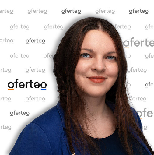 Portret kobiety z długimi, ciemnymi włosami splecionymi w warkocze, ubrana w niebieską marynarkę, na tle ściany z powtarzającym się logo Oferteo.