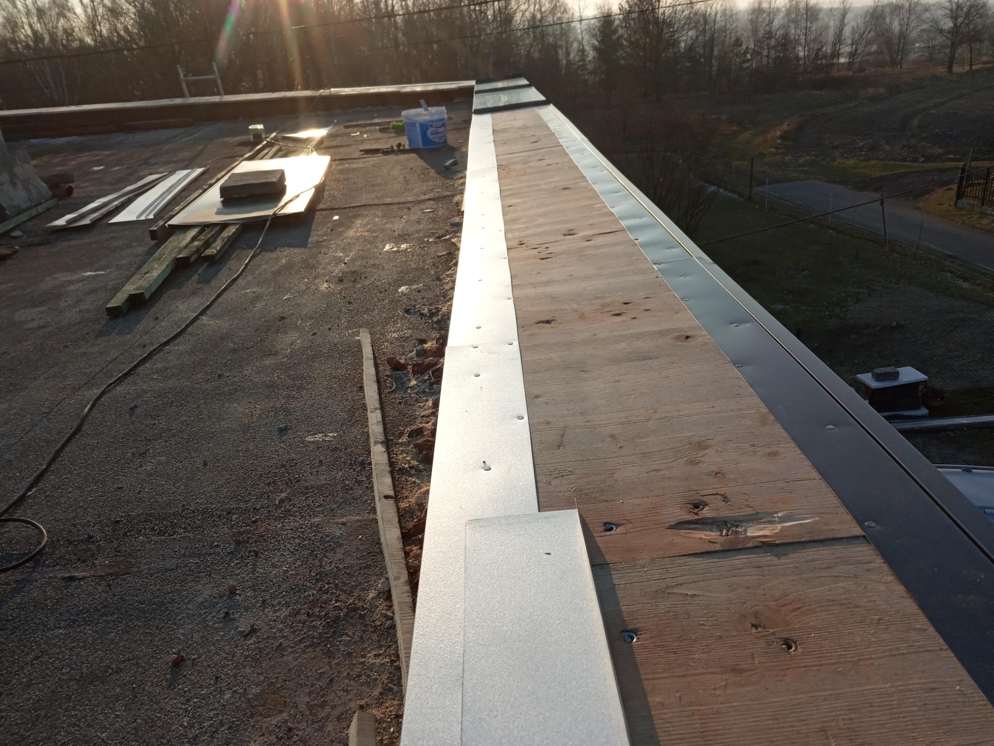 Montaż obróbek blacharskich na dachu w Raciborzu, widoczne deski, blacha, narzędzia i elementy konstrukcyjne dachu w trakcie prac.