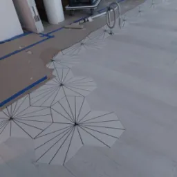 Fragment podłogi w trakcie montażu: heksagonalne płytki z geometrycznym wzorem łączą się z jasnymi panelami, widoczne zabezpieczenia podłoża i sprzęt do sprzątania.