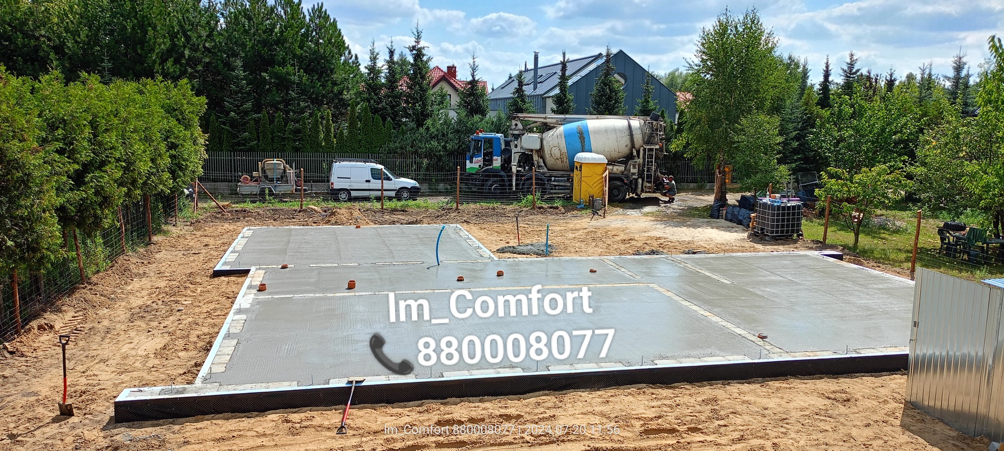 Świeżo wylany beton na fundamentach domu jednorodzinnego, widoczny mikser do betonu w tle, teren budowy w słoneczny dzień.