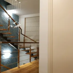 Nowoczesne schody drewniane z metalowymi elementami i dekoracyjną tapetą w tle, oświetlone lampą w kształcie ptaków, zrealizowane w Jeleniej Górze.