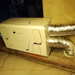 Centrala wentylacyjna z rekuperacją zamontowana na poddaszu, widoczne srebrne rury wentylacyjne i drewniane elementy konstrukcyjne dachu.