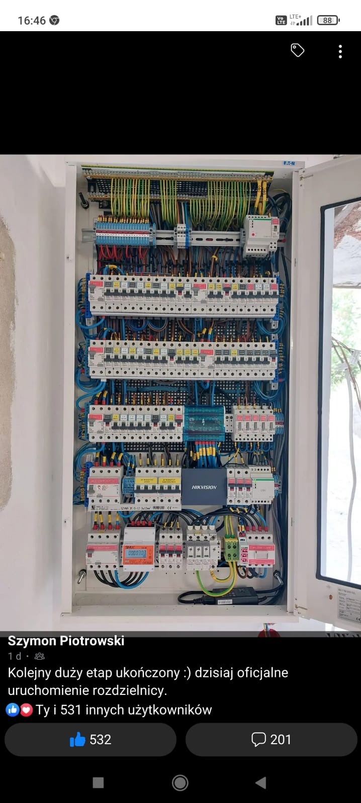 Otwarta skrzynka rozdzielcza z licznymi bezpiecznikami, przewodami i elementami sterującymi, zamontowana na ścianie, widoczne okablowanie i podłączenia.