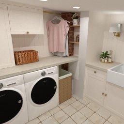 MZ InteriorDesign - Projekt pralni w stylu farmhouse: białe szafki, pralka, suszarka, złota armatura, drewniane półki i ceglany akcent. Jasne, przytulne wnętrze.