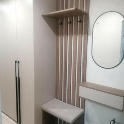 Yury Feldberh - Nowoczesny przedpokój z szafą w zabudowie, panelem w pionowe pasy z wieszakami, półką, siedziskiem i owalnym lustrem.