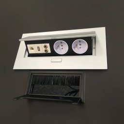Yury Feldberh - Wpuszczane w blat biurka gniazda elektryczne i porty komunikacyjne (RJ45, USB) z otwieraną klapką oraz przepust kablowa z szczotkowym uszczelnieniem i uchylną osłoną.