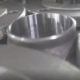 Gładkie, metalowe pierścienie i tuleje z widocznymi śladami obróbki skrawaniem, leżące blisko siebie; na jednym z pierścieni widoczne oznaczenia 'P2-50'.