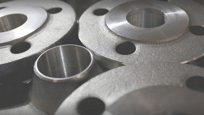 Grupowe ujęcie metalowych kołnierzy i tulei z widoczną fakturą obróbki skrawaniem, ułożonych blisko siebie.