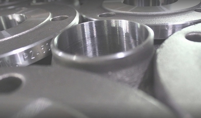 Gładkie, metalowe pierścienie i tuleje z widocznymi śladami obróbki skrawaniem, leżące blisko siebie; na jednym z pierścieni widoczne oznaczenia 'P2-50'.