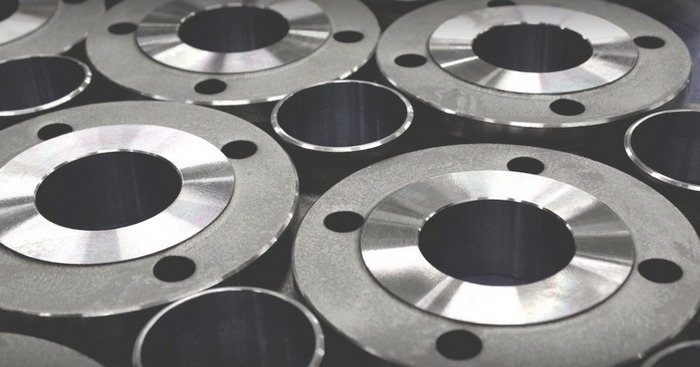 Metalowe kołnierze i krótkie odcinki rur, widoczne otwory montażowe, szara kolorystyka, matowe wykończenie.