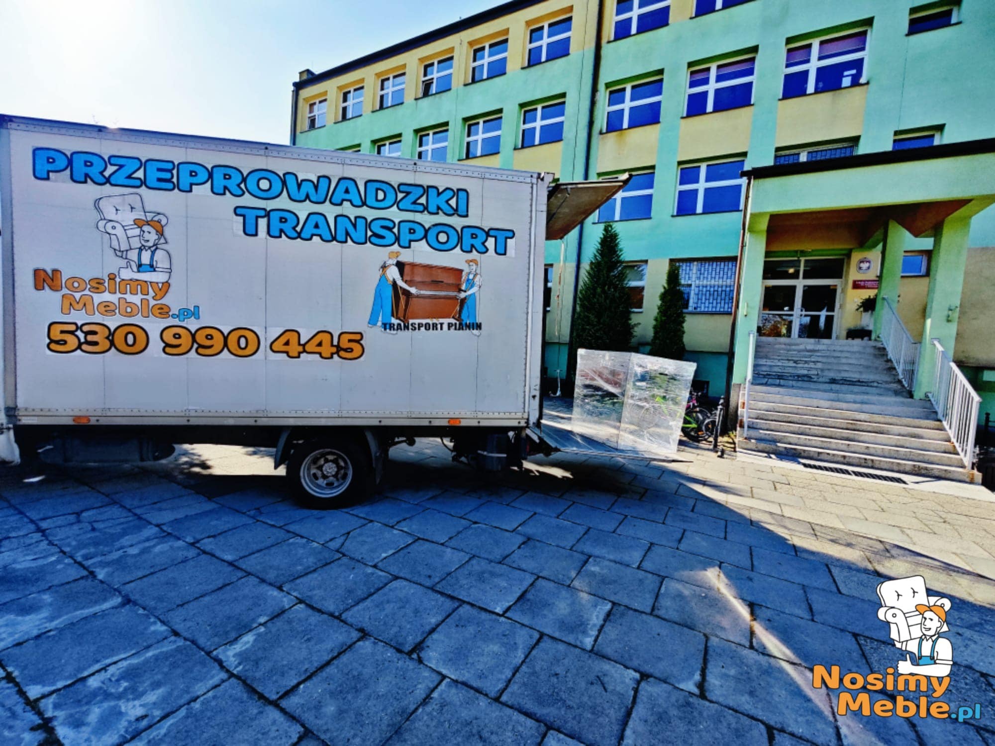 Samochód dostawczy z reklamą firmy transportowej zaparkowany przed budynkiem z niebiesko-żółtą elewacją, na samochodzie widnieją napisy 'Przeprowadzki Transport' oraz grafiki przedstawiające...
