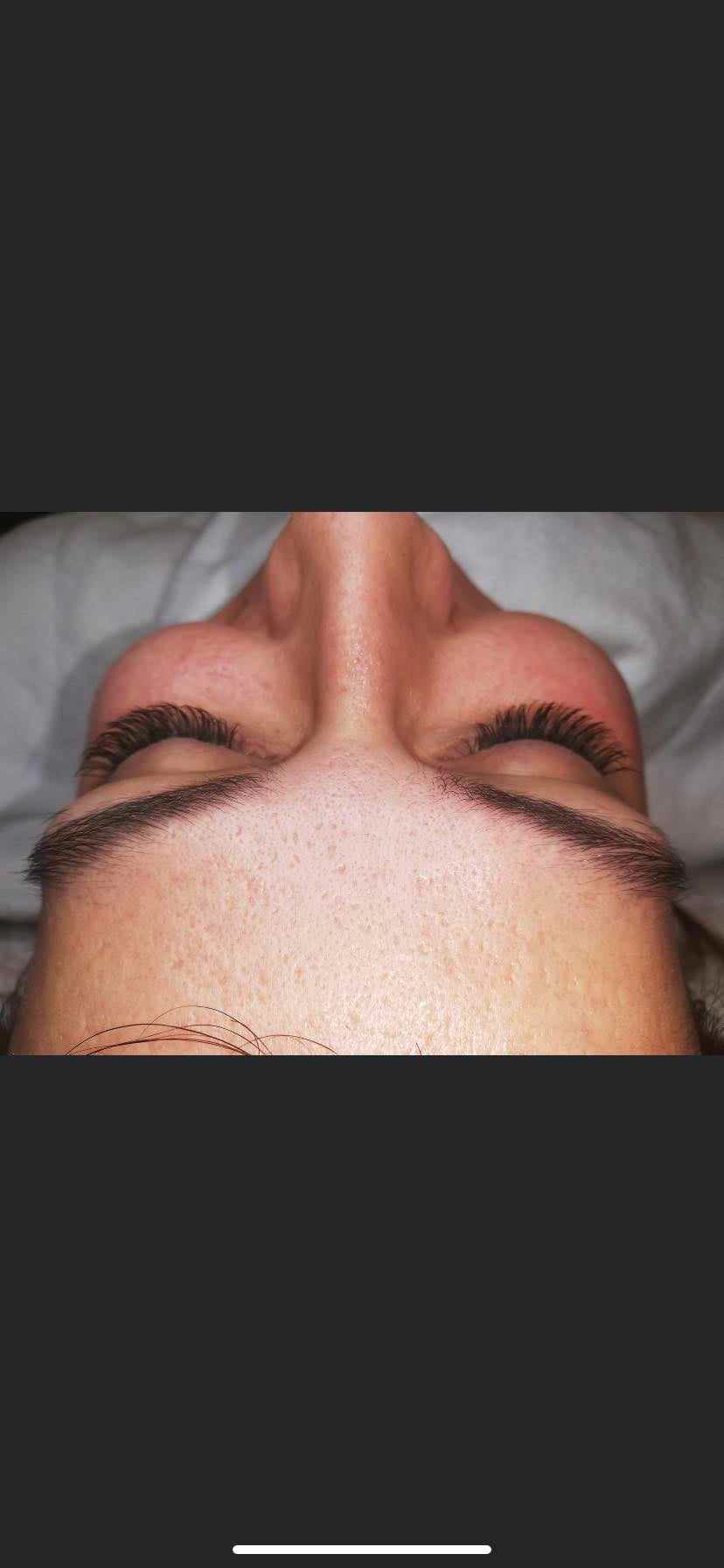 Zbliżenie na twarz kobiety leżącej na plecach, z widocznymi, świeżo przedłużonymi rzęsami i wyregulowanymi brwiami.