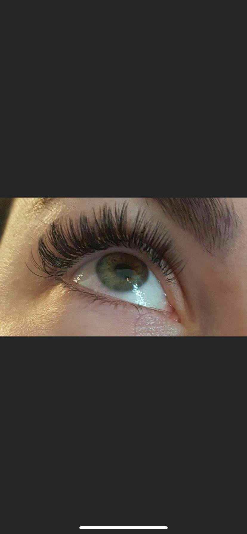 Zbliżenie na oko z zieloną tęczówką i przedłużonymi, gęstymi rzęsami w stylu 'kociego oka'.