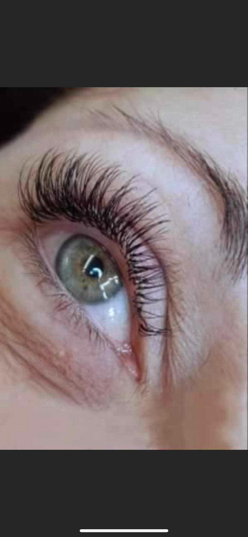 Zbliżenie na oko z zieloną tęczówką i wyraźnie przedłużonymi, czarnymi rzęsami; widoczny delikatny makijaż brwi.