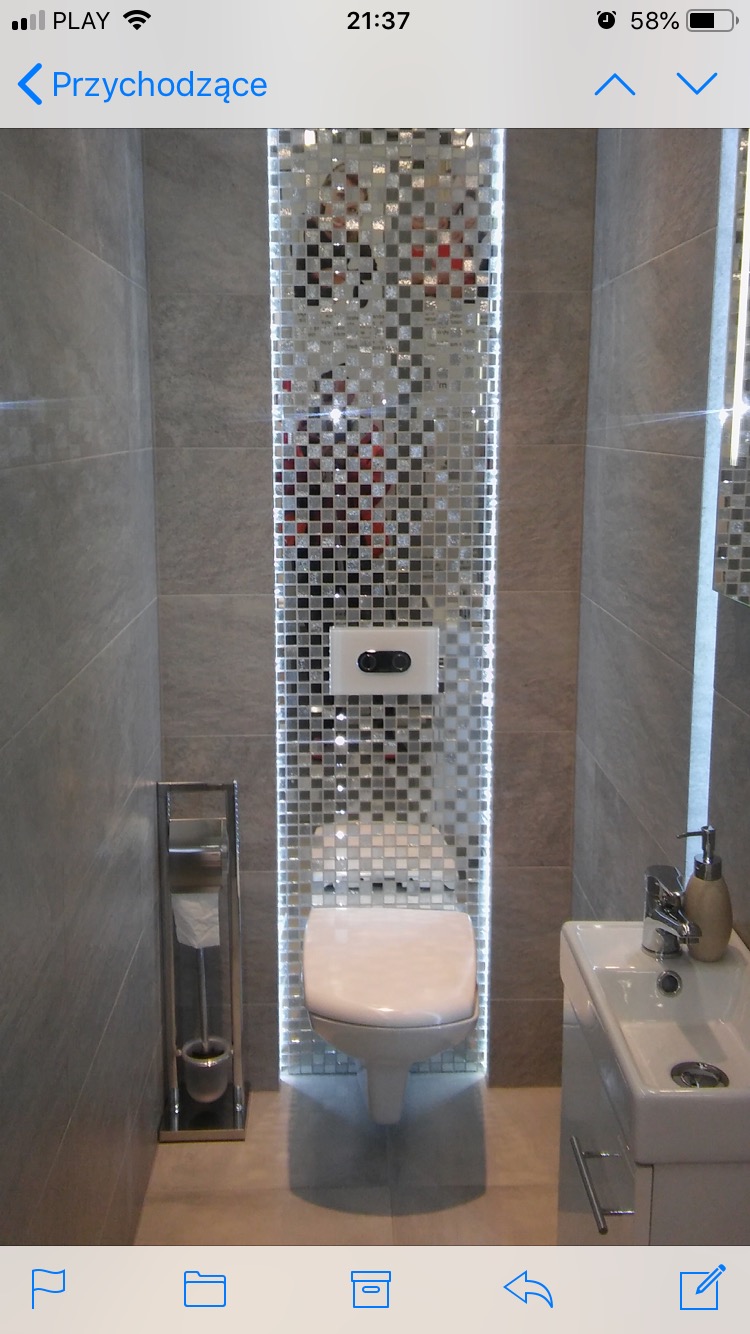 Nowoczesna łazienka z toaletą podwieszaną i ścianą z lustrzanych mozaiek, oświetlona pionowymi paskami LED.