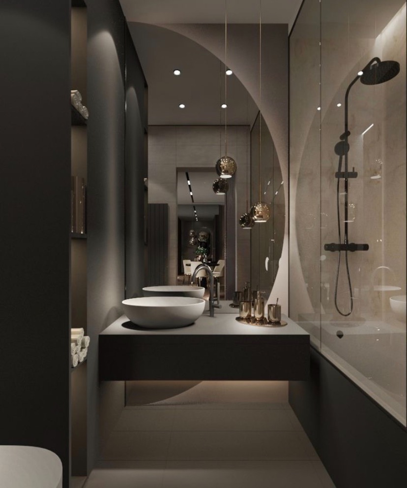 Nowoczesna łazienka z dwoma okrągłymi umywalkami na blacie w kolorze grafitu, szklana kabina prysznicowa i wiszące lampy z metalicznymi kloszami.