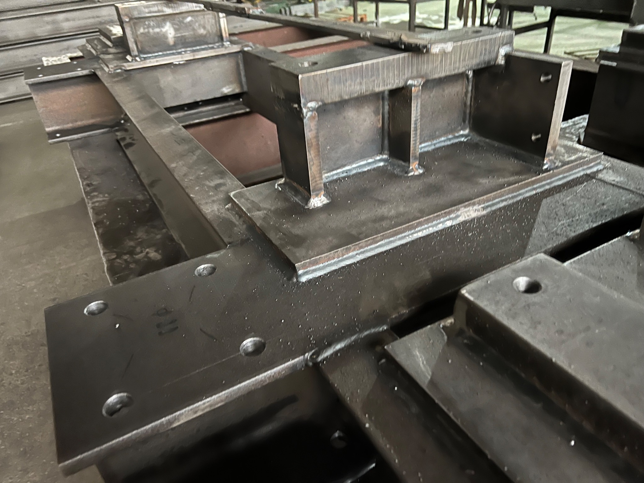 Metalowe elementy konstrukcyjne po spawaniu, widoczne spoiny i otwory montażowe, przygotowane do dalszej obróbki lub montażu.