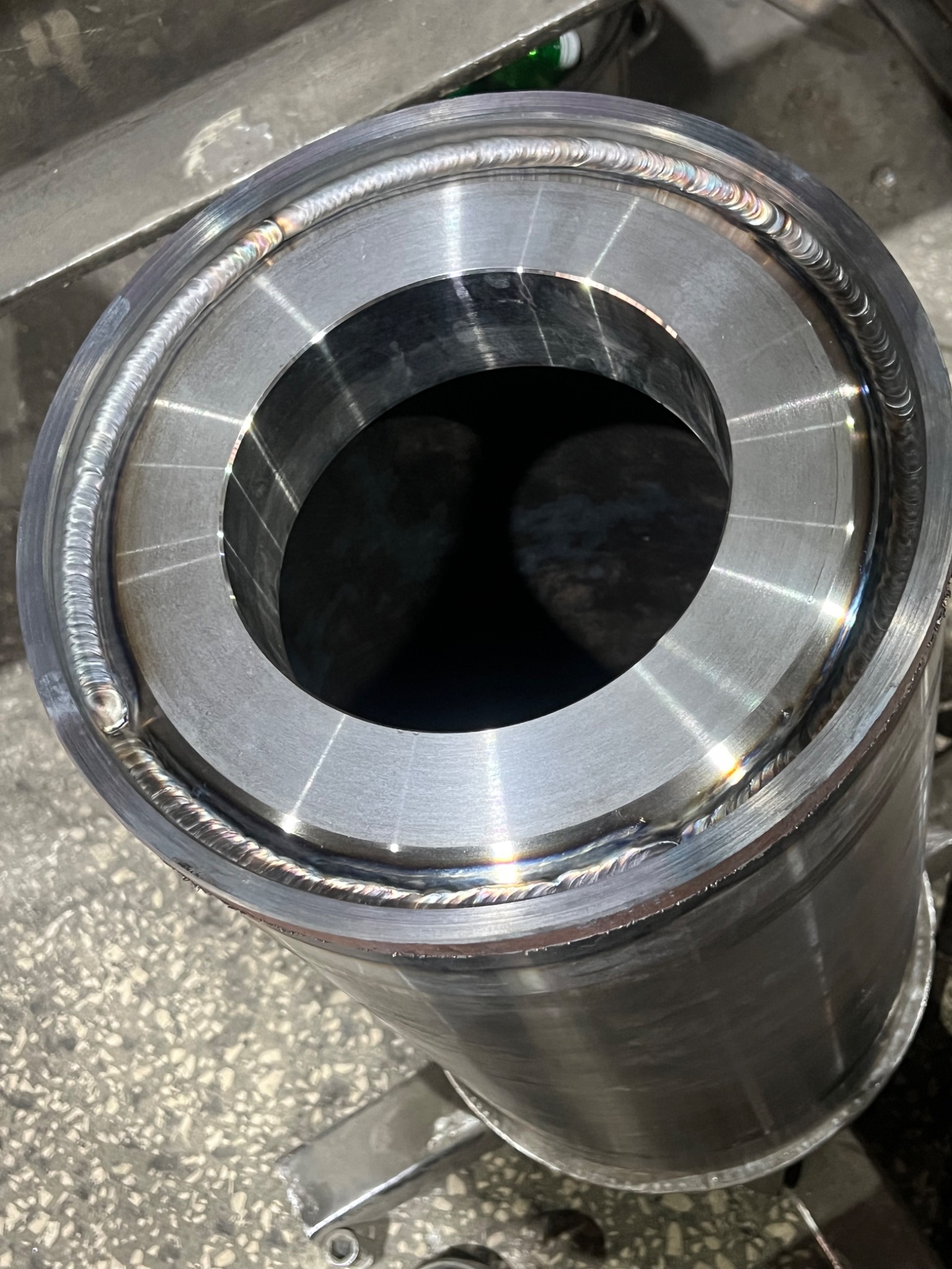 Metalowy cylinder z precyzyjnym spoinem okrężnym, widoczne ślady obróbki i charakterystyczne przebarwienia po spawaniu.