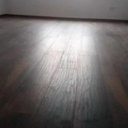 Ułożona ciemnobrązowa podłoga panelowa w pustym pokoju z białymi ścianami i listwami przypodłogowymi, widoczne gniazdka elektryczne.