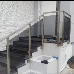 Marta Gałka Usługi - Zewnętrzne schody z czarnego kamienia z balustradą ze stali nierdzewnej i szkła, widoczne narzędzia na górnym podeście, jasna elewacja budynku w tle.