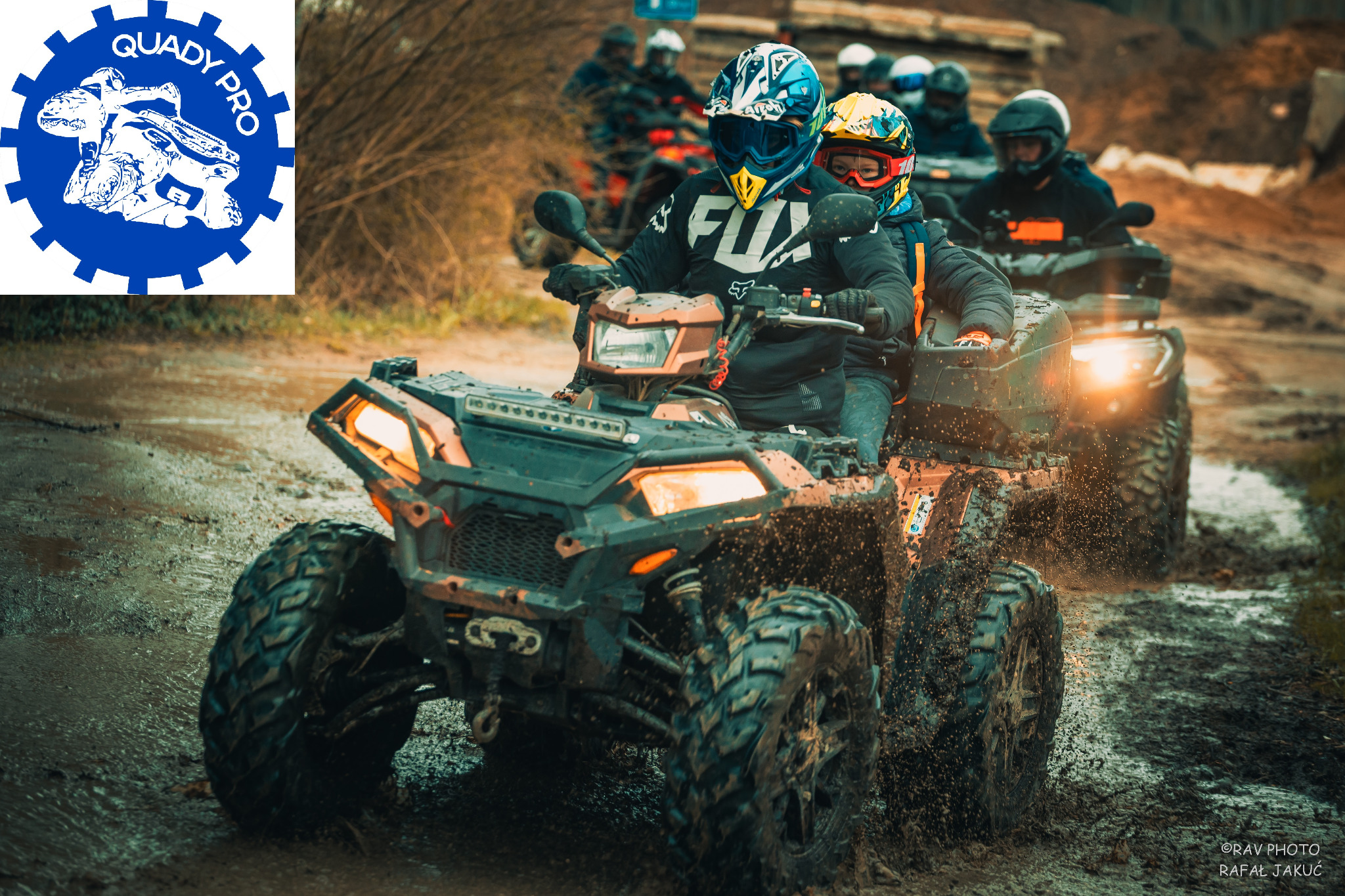Grupa osób na quadach w kaskach i goglach, jadących po błotnistym terenie, z logo firmy Quady Pro w lewym górnym rogu.