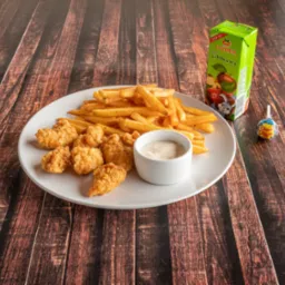 Frytki, nuggets z kurczaka i dip w białej miseczce na białym talerzu, obok kartonik soku jabłkowego i lizak Chupa Chups, na drewnianym stole.