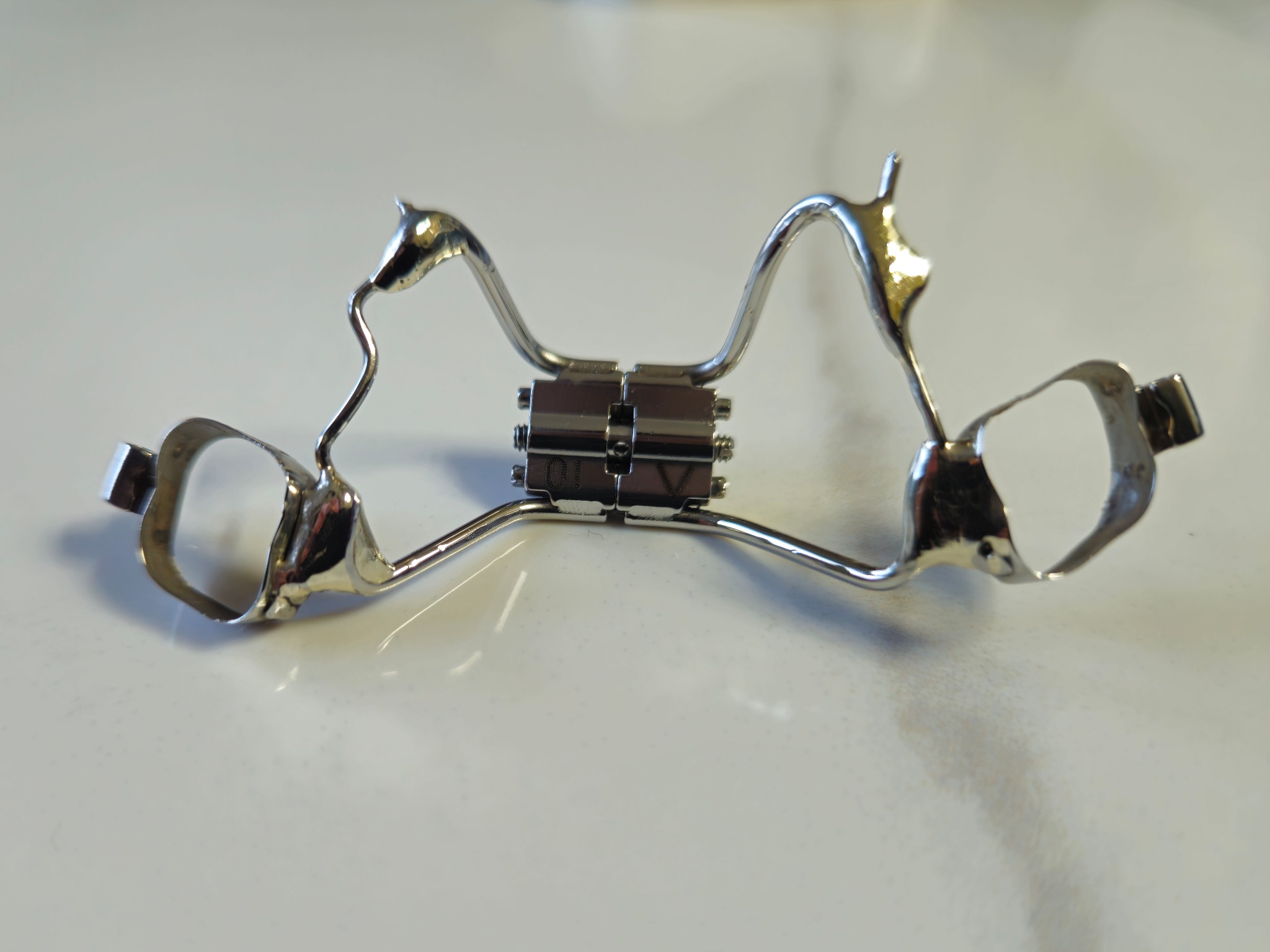 Aparat ortodontyczny typu Hyrax z elementami w kształcie głowy konia, leżący na białym tle.