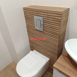 Bud Rud - Nowoczesna toaleta podwieszana z obudową z drewnopodobnych paneli, chromowany przycisk spłukiwania, białe płytki i umywalka nablatowa. Wykończenie łazienki.