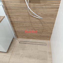 Bud Rud - Nowoczesna kabina prysznicowa z drewnopodobną okładziną ścienną i odpływem liniowym. Jasne płytki podłogowe imitujące drewno. Minimalistyczny design.