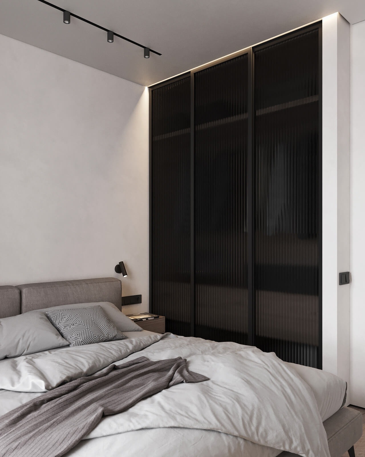 Minimalistyczna sypialnia z łóżkiem w odcieniach szarości, ciemną ścianą szafy z ryflowanymi drzwiami przesuwnymi i punktowym oświetleniem sufitowym.