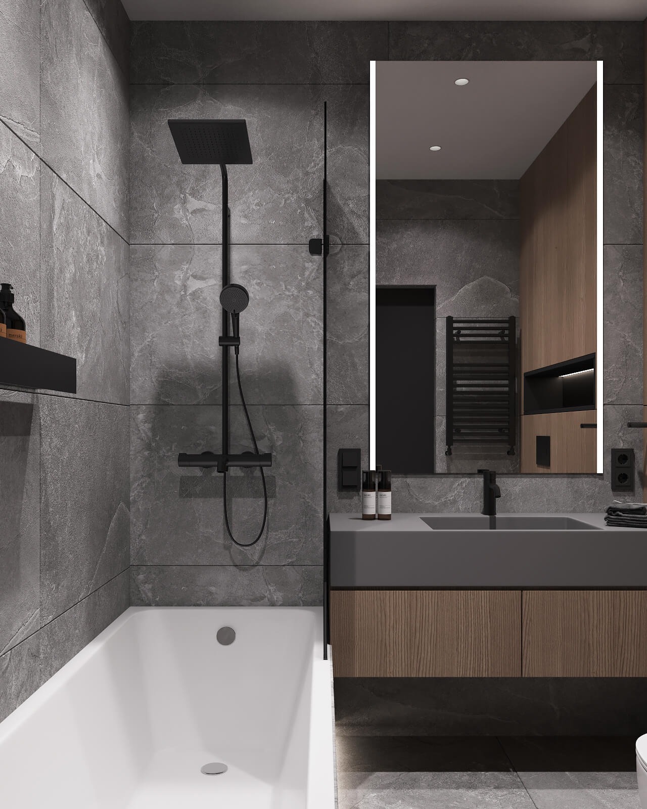Nowoczesna łazienka z szarymi płytkami imitującymi kamień, białą wanną i umywalką z szarą, matową powierzchnią oraz drewnianą szafką pod nią. W tle podświetlane lustro LED.