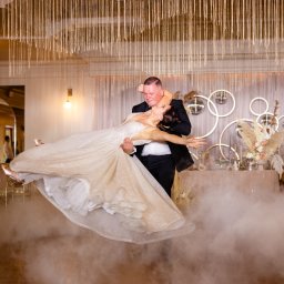 PHU KAR-EVENTS - Para młoda podczas pierwszego tańca w chmurach dymu, sala udekorowana kwiatami i lustrzanymi kulami.