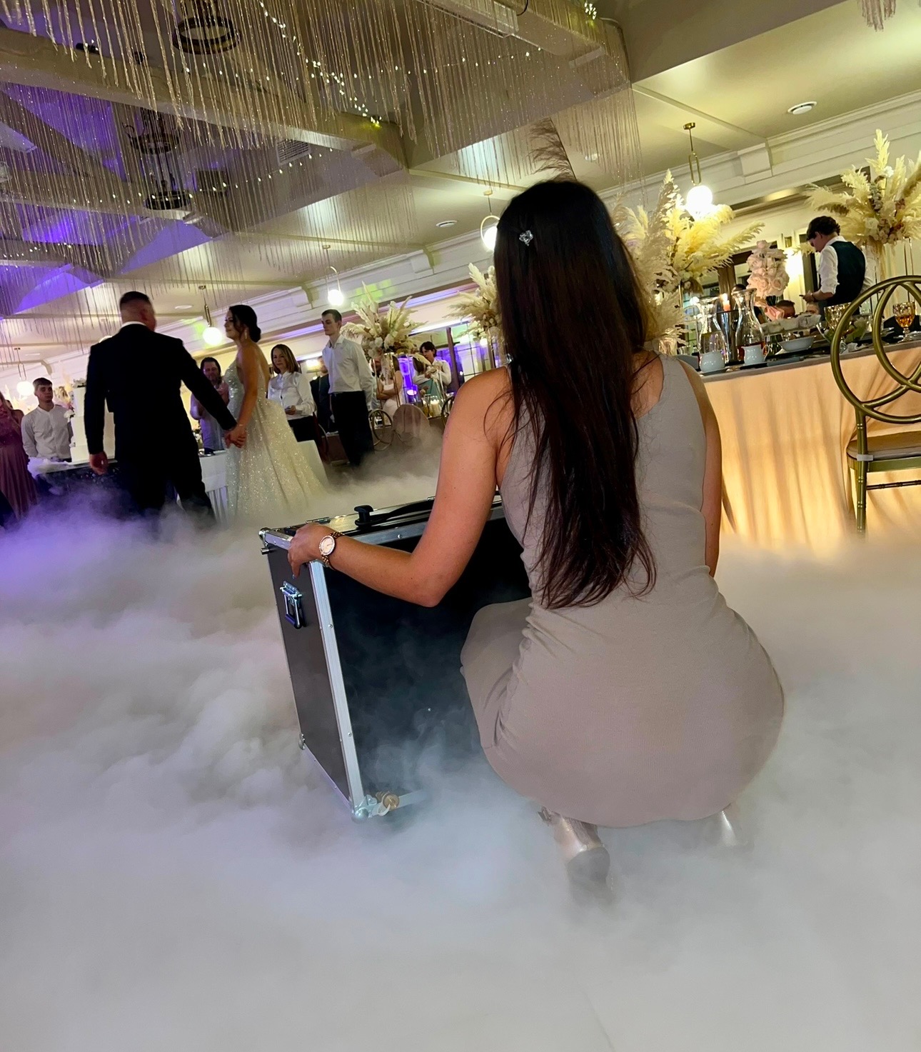 Obsługa ciężkiego dymu na parkiecie podczas pierwszego tańca pary młodej, widok zza urządzenia.