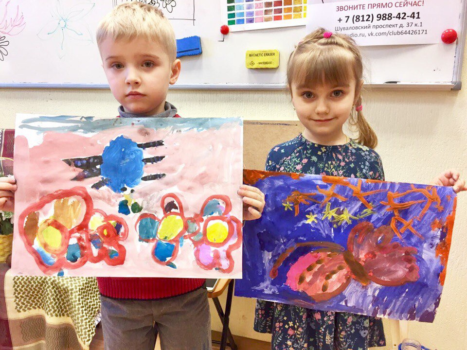 Dwoje dzieci prezentuje swoje obrazy malowane farbami na papierze; chłopiec trzyma pracę z abstrakcyjnym motywem kwiatów i nieba, a dziewczynka obraz z motywem nocnego nieba i roślinności.