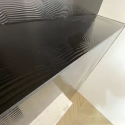 Położone, błyszczące płytki ścienne w odcieniach czerni i bieli z dekoracyjnym, falistym wzorem, uzupełnione parkietem ułożonym w jodełkę.