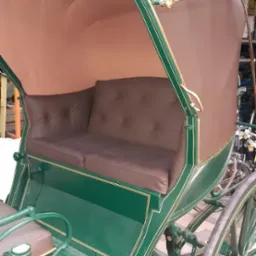 Odrestaurowany powóz konny z zieloną karoserią, brązowym dachem i skórzaną tapicerką siedzeń z guzikami