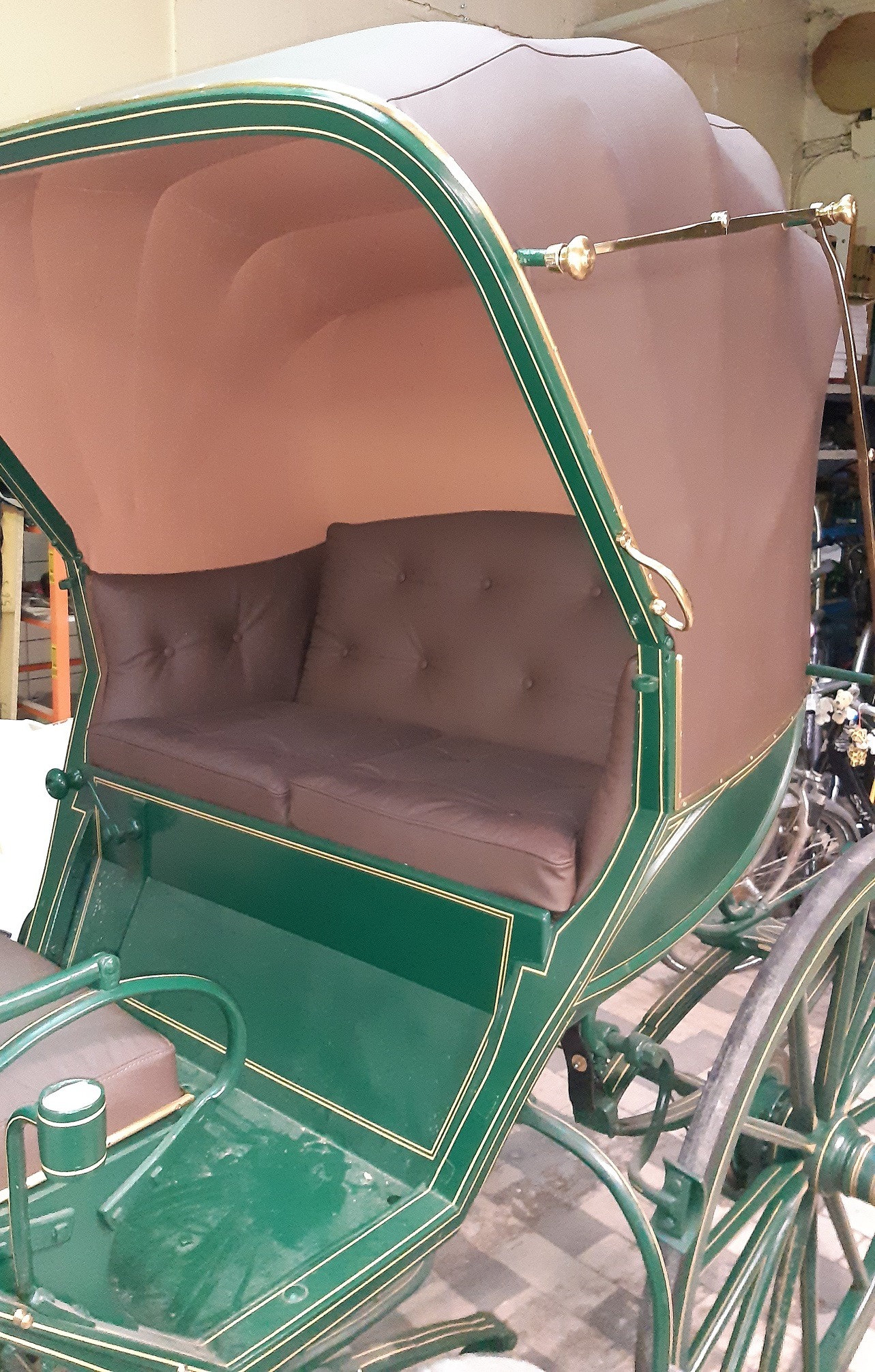 Odrestaurowany powóz konny z zieloną karoserią, brązowym dachem i skórzaną tapicerką siedzeń z guzikami