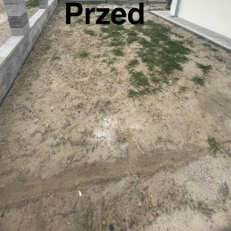 Usługi Czyszczące Robert Minikowski - Zdjęcie 'przed' realizacji ogrodu: piaszczysta ziemia z chwastami, obrzeża z szarej kostki, fragment ściany budynku. Ujęcie z góry, widoczny stan początkowy.