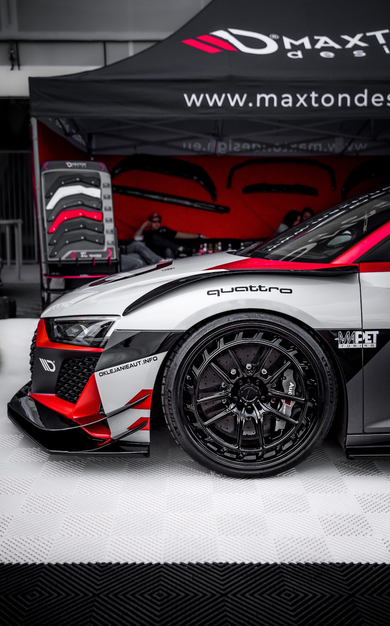 Zmodyfikowane Audi R8 z czarnymi felgami, czerwonymi akcentami i naklejkami tuningowymi na tle stoiska Maxton Design.