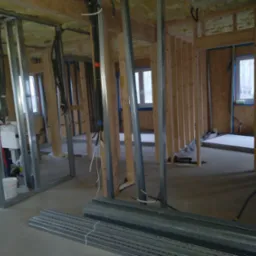 Konstrukcja szkieletowa ścian działowych z profili metalowych i drewnianych łat, widoczne instalacje, przygotowanie do montażu płyt karton-gips.