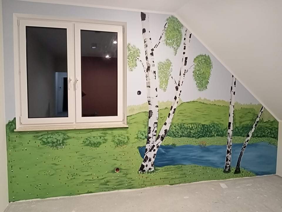 Ręcznie malowana ściana w pokoju dziecięcym przedstawiająca krajobraz z brzozami i jeziorem, widoczna pod oknem oraz na skośnej ścianie poddasza.